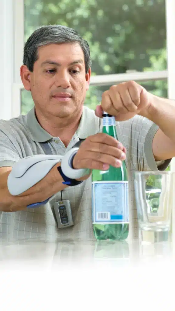 אדם מתרגל אחיזת בקבוק עם מערכת Bioness H200 Wireless על האמה והיד